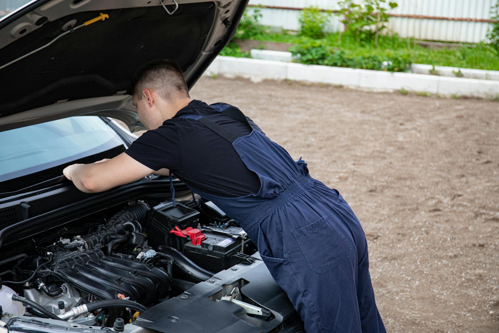 Mechanic diagnosing car air conditioning system outdoors in Oklahoma City